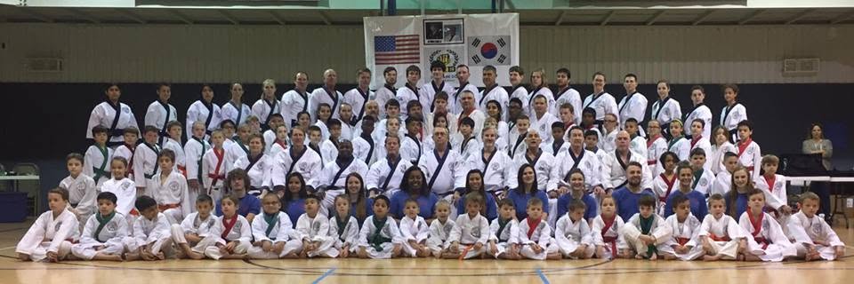 Carthage Karate & Fitness — full class of students posing in the dojo with Taekwondo flags